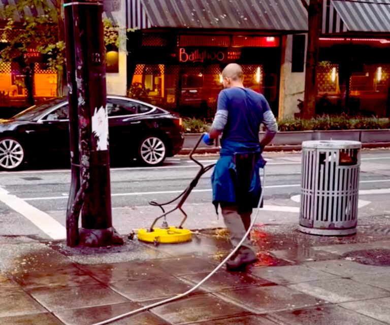 Pressure washing a sidewalk in downtown